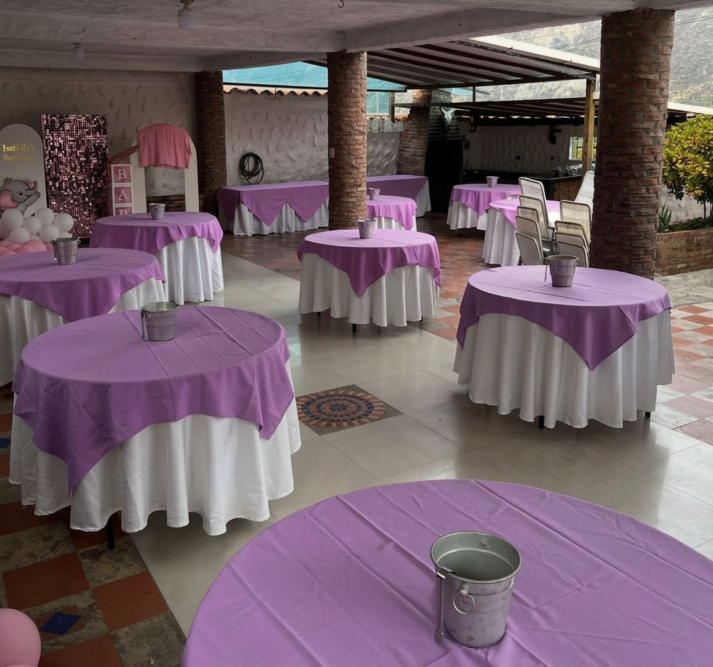 Salón con mesas redondas vestidas con sobremanteles lila